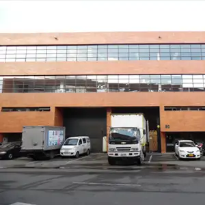 Fachada de un edificio industrial con camiones de carga en el acceso.
